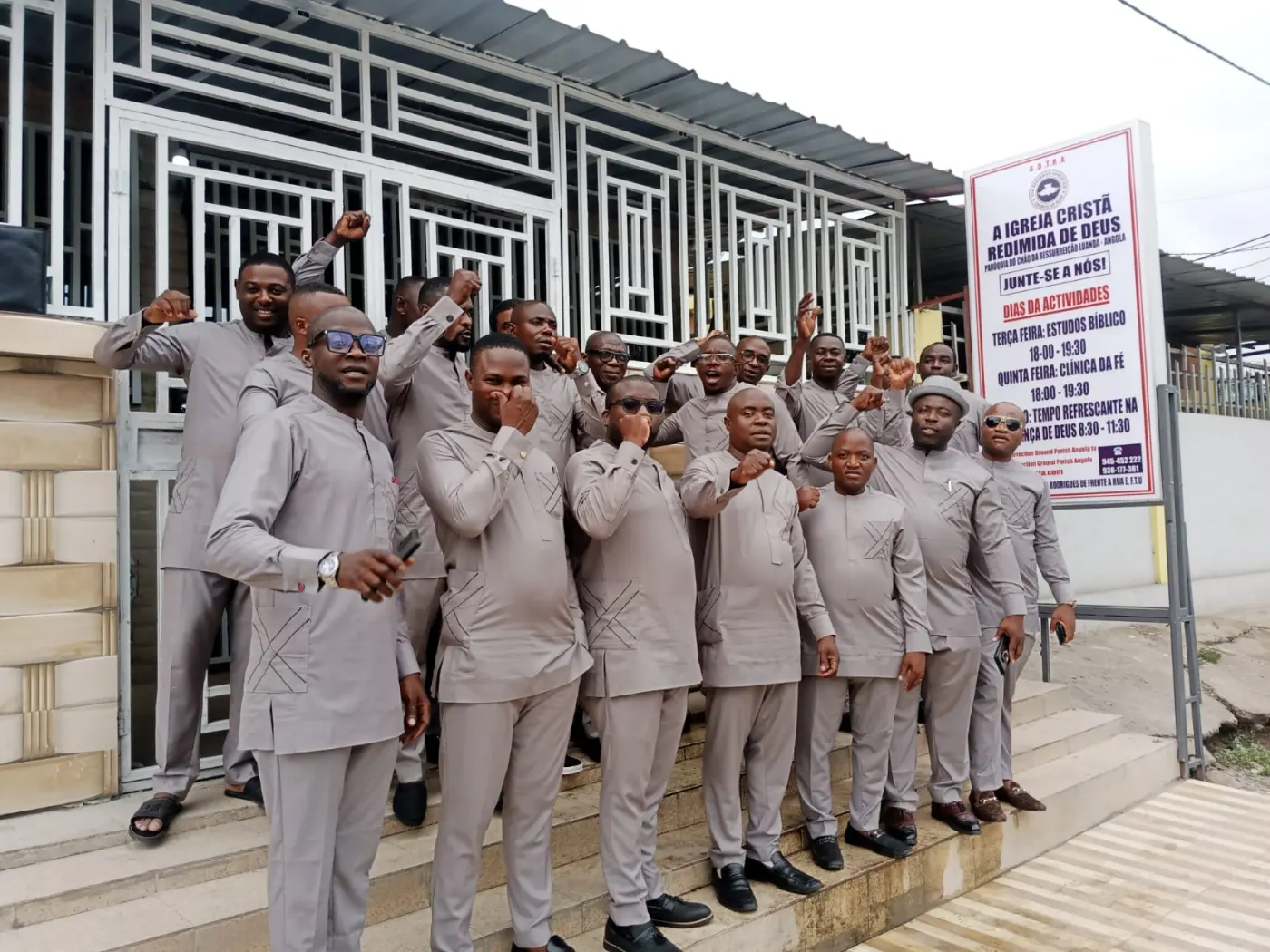 Men of Resurrection Ground Parish in matching grey suits, posing together outside the church