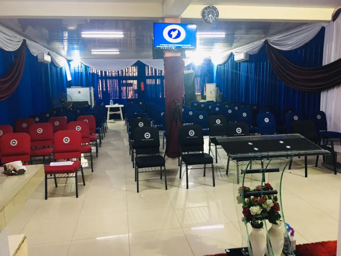 The sanctuary at Resurrection Ground Parish with rows of chairs, blue curtains and the RCCG emblem